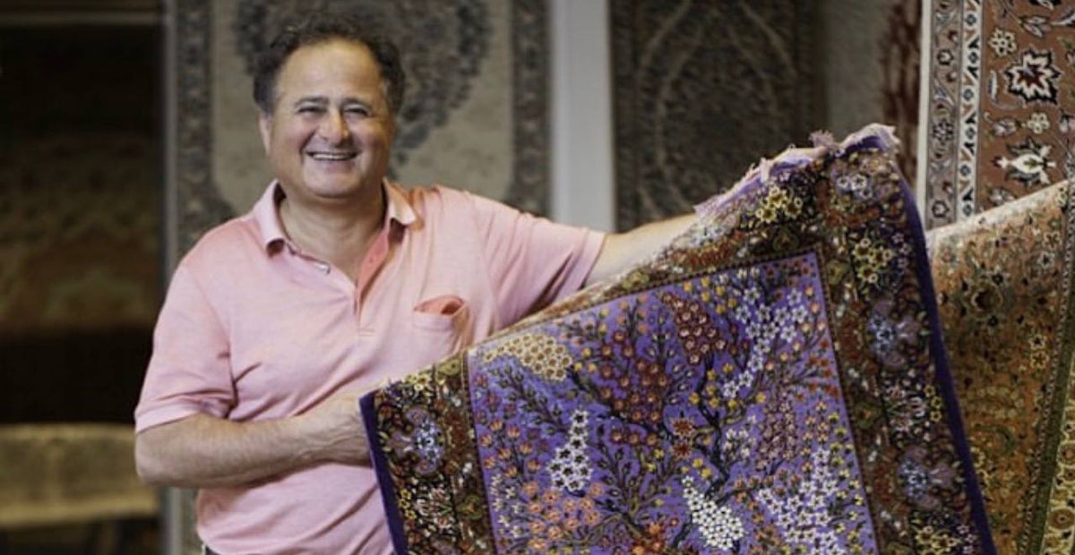 Inhaber von Hafez Orient im Ladengeschäft mit einem handgeknüpften Ghom-Seidenteppich